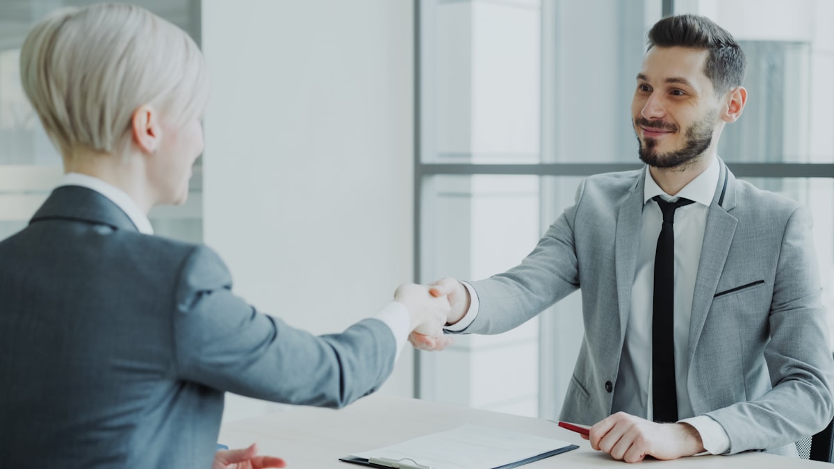 Advisor and client shaking hands across a table
